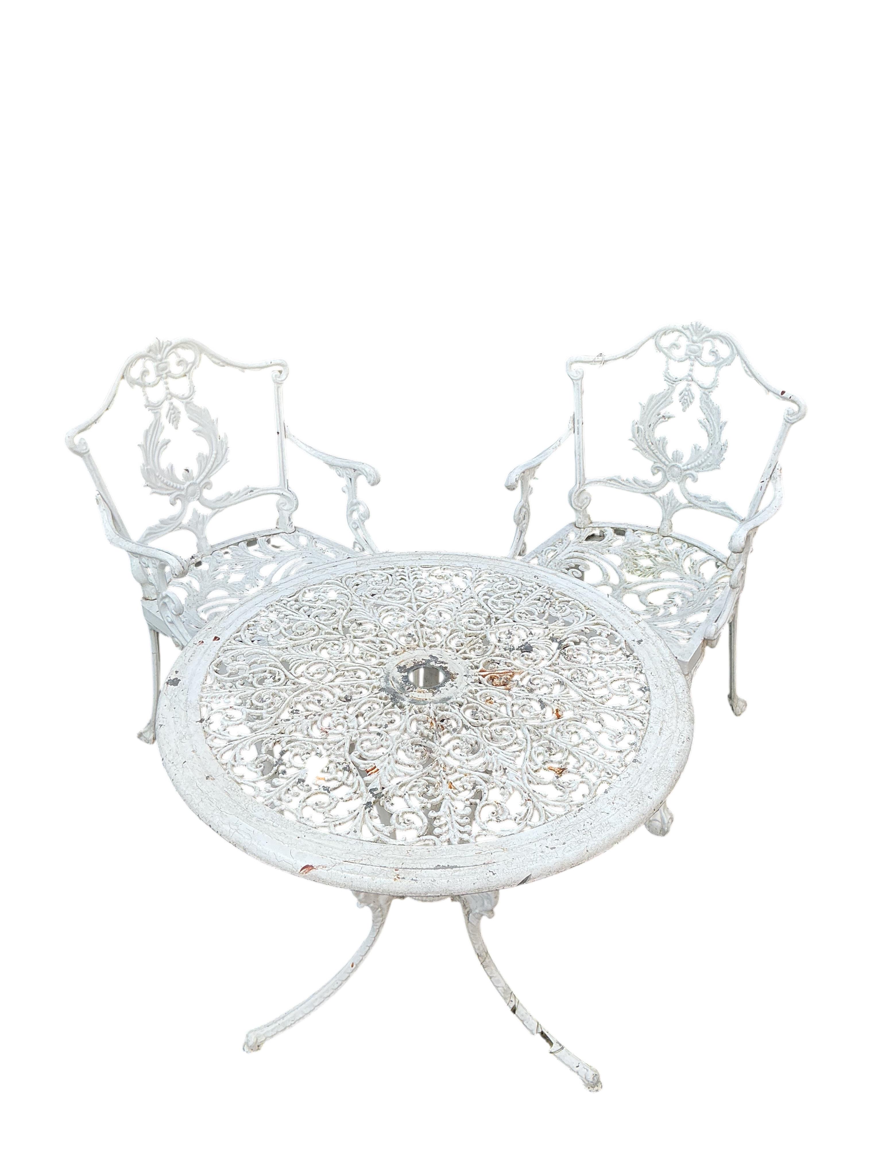 A Victorian style circular painted aluminium garden table, diameter 68cm, height 65cm together with two elbow chairs